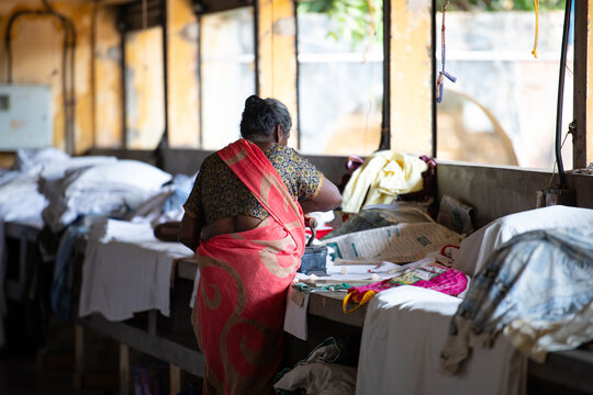 Woman in traditional clothes irons with an antique charcoal iron, Dhobi Ghat, open air laundry in Kochi, India