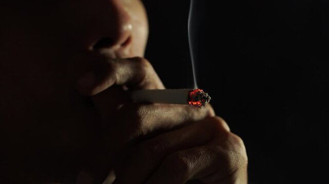 an adult man is smoking a cigarette deeply. this footage illustrates the dangers of smoking and can make a person addicted to it.