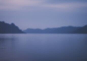 Fototapeta premium Blurry Photo of Calm Lake and Mountains at Dusk