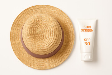 Straw sun hat with SPF 30 sunscreen tube – summer essentials flatlay on white background