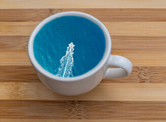 blue or turquoise summer sea with waves and boats in a cup of coffee or tea. Take a travel lake a coffee. Tourism concept foe a season trip