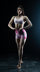 Obraz premium Young beautiful fitness woman on a black background. Fitness girl, female bodybuilder on a dark background 