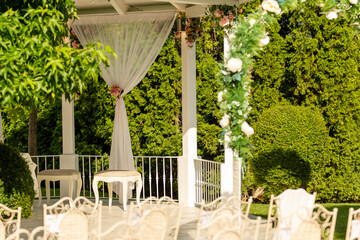 Elegant outdoor gazebo decorated with flowers and sunlight in a serene garden setting