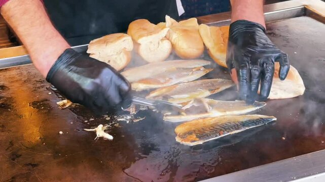 A street food vendor grills mackerel and warms bread on a swaying boat to prepare balik ekmek, a classic Turkish fish sandwich