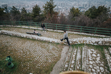 Friends explore a scenic lookout on a hill surrounded by trees under a cloudy sky, capturing the essence of outdoor leisure and natural beauty.