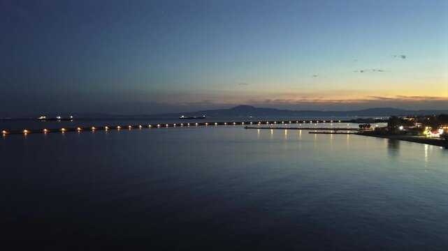 Aerial push in footage, flying towards iconic one kilometer Pier at port of Kalamata, Peloponnesus, Greece. Golden hour , dusk, beautiful sunset 4K