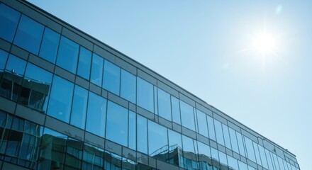 Obraz premium Modern building exterior reflecting sky and sunlight, glass facade architecture, urban skyline