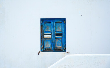 Old rustic blue wooden window on a white wall in Aegiali, Amorgos island, Greece – traditional...