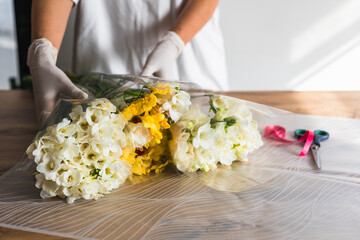 Florist preparing beautiful bouquets with colorful flowers in a bright workspace