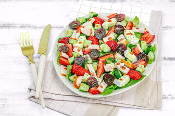Fresh salad with strawberry, leaves mix, brie cheese, ripe grape and smoked chicken