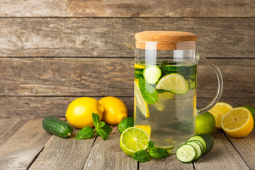 Cucumber water with lemon, lime and mint on a wooden table. Water infused with sliced...