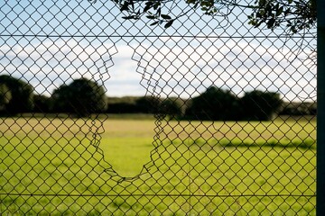 Hole in chain link fence &ndash; damaged wire mesh close-up detail