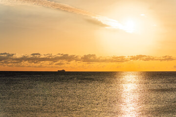 A serene image featuring the tranquil view of a ship against a sunset sky, accentuating the beauty of the open sea