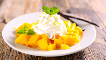 Delight in refreshing dessert featuring ripe mango chunks topped with creamy whipped topping, garnished with mint leaves and hint of vanilla. Perfect for summer enjoyment