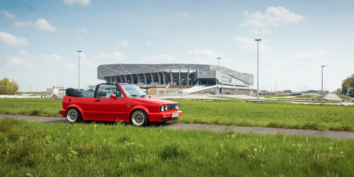 Red Volkswagen Golf mk2 cabriolet near Arena Lviv. Side view of 1990s red VW, stadium in the background. Lviv, Ukraine - May 02 2014.