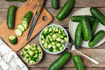 Cucumber on wooden background. Slice of cucumber on background. Fresh organic green cucumbers gherkin. Vegan. Salad ingredient. Farm vegetables. Cut vegetables with knife. Space for text. Copy space