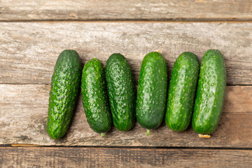 Cucumber on wooden background. Slice of cucumber on background. Fresh organic green cucumbers gherkin. Vegan. Salad ingredient. Farm vegetables. Cut vegetables with knife. Space for text. Copy space