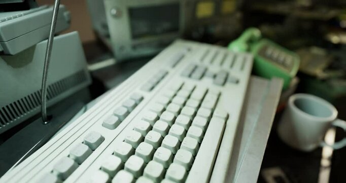 A nostalgic workspace filled with vintage technological devices, featuring a retro keyboard, old monitors, and various gadgets scattered across a desk in soft lighting.