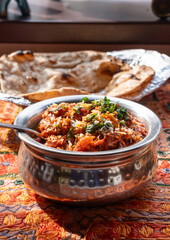 Lamb curry with tomatoes and fiery chili, traditional Indian Laal Maas served in a metal dish