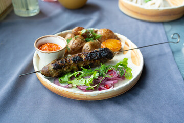 Georgian lula kebab plate. Bbq skewer, traditional barbecue dish with baked potatoes, sauce