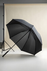 Black umbrella mockup with open canopy on neutral background, minimalist presentation ideal for branding, product display, or rain gear advertisement