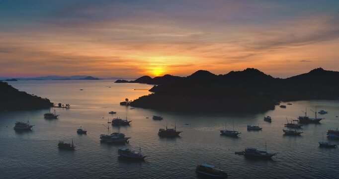 Many traditional boats floating near the coast of Ende, Flores Island, Indonesia during a breathtaking sunset illuminating the landscape with warm colors