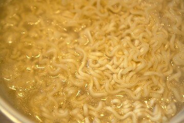 Boiling pot of curly yellow noodles in steaming broth