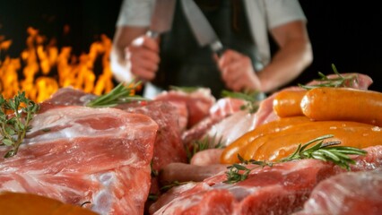 Large assortment of premium raw meat, beef, sausages, pork and chicken suitable for butchery advertising, fire on background