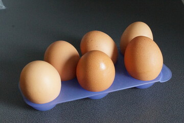 An assortment of eggs rests gently on a neutral surface, highlighting their perfect curves and smooth shells. Natural light grazes their surface, revealing subtle shades ranging from bright white to w