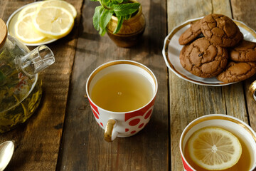 Rustic tea party. Mugs of green herbal tea with lemon on wooden table. 