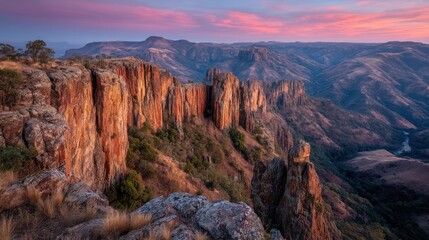 Obraz premium Rocky cliffs and mountains under a colorful sky at dusk or dawn.
