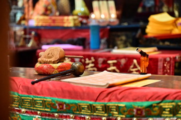 A close-up of a wooden fish and a Buddhist sutra resting on a temple offering table. The scene captures the tools used in daily chanting, echoing spiritual devotion and tradition.