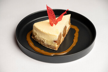 Crunchy Peanut Caramel Chocolate Tart (Eggless) – A rich, indulgent tart layered with crunchy peanuts, gooey caramel, and smooth chocolate, served in a black plate on a white background.