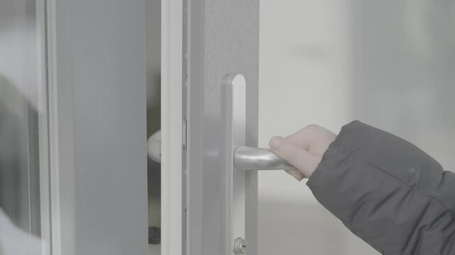A child in a black jacket opens the handle of a glass door. Slog-3