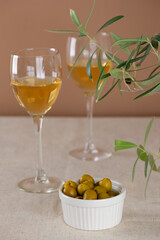 Olives with two glasses of white non-alcoholic wine on the table. Vertical orientation.