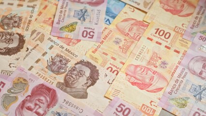 Mexican pesos banknotes scattered on a flat surface, displaying various denominations and intricate designs from banco de mÃ©xico.