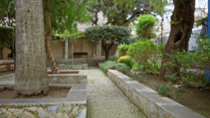 Garden scene with a mediterranean atmosphere featuring blurred trees and greenery, creating a bokeh effect in an old stone pathway setting, presenting a serene defocused view.