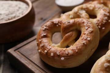 Tasty salted pretzels on wooden board, closeup