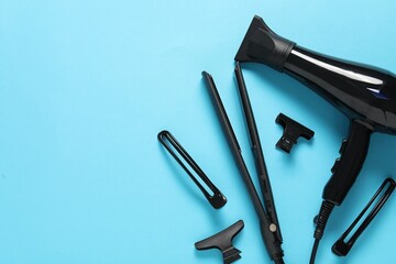 Different hairstyling tools on light blue background, flat lay. Space for text