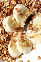 Closeup of Greek Yogurt with Granola. Homemade Oats Granola with Almonds, Seeds, Walnuts, Fresh Greek Yogurt and Banana Slices Closeup. Healthy Breakfast, Morning Nutrition.