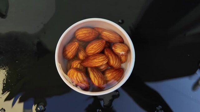 Almonds falling on the black table with one cup of water and almond.  water splashing, Slow motion footage , healthy nuts intro
