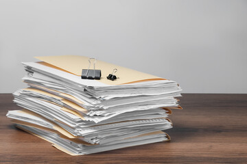 File folders with papers and binder clips on wooden table against gray background