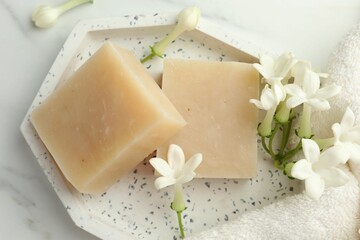 Bars of soap and jasmine flowers on white marble table, flat lay