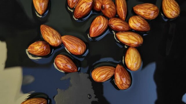 almonds on water  ,throwing punch almonds on black background board , slow motion