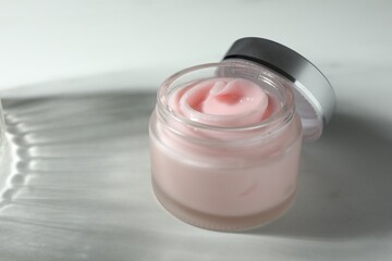 Jar of moisturizing body cream on white table, closeup