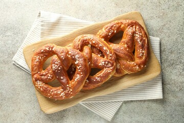 Tasty pretzels with salt on grey table, top view