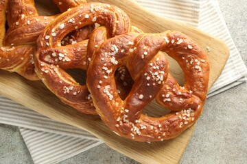 Tasty pretzels with salt on grey table, top view