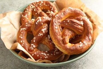 Tasty pretzels with salt on grey table, closeup
