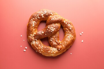 Tasty pretzel with salt on red background, top view