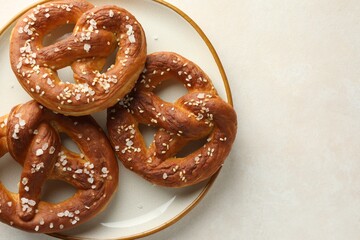 Tasty pretzels with salt on white table, top view. Space for text